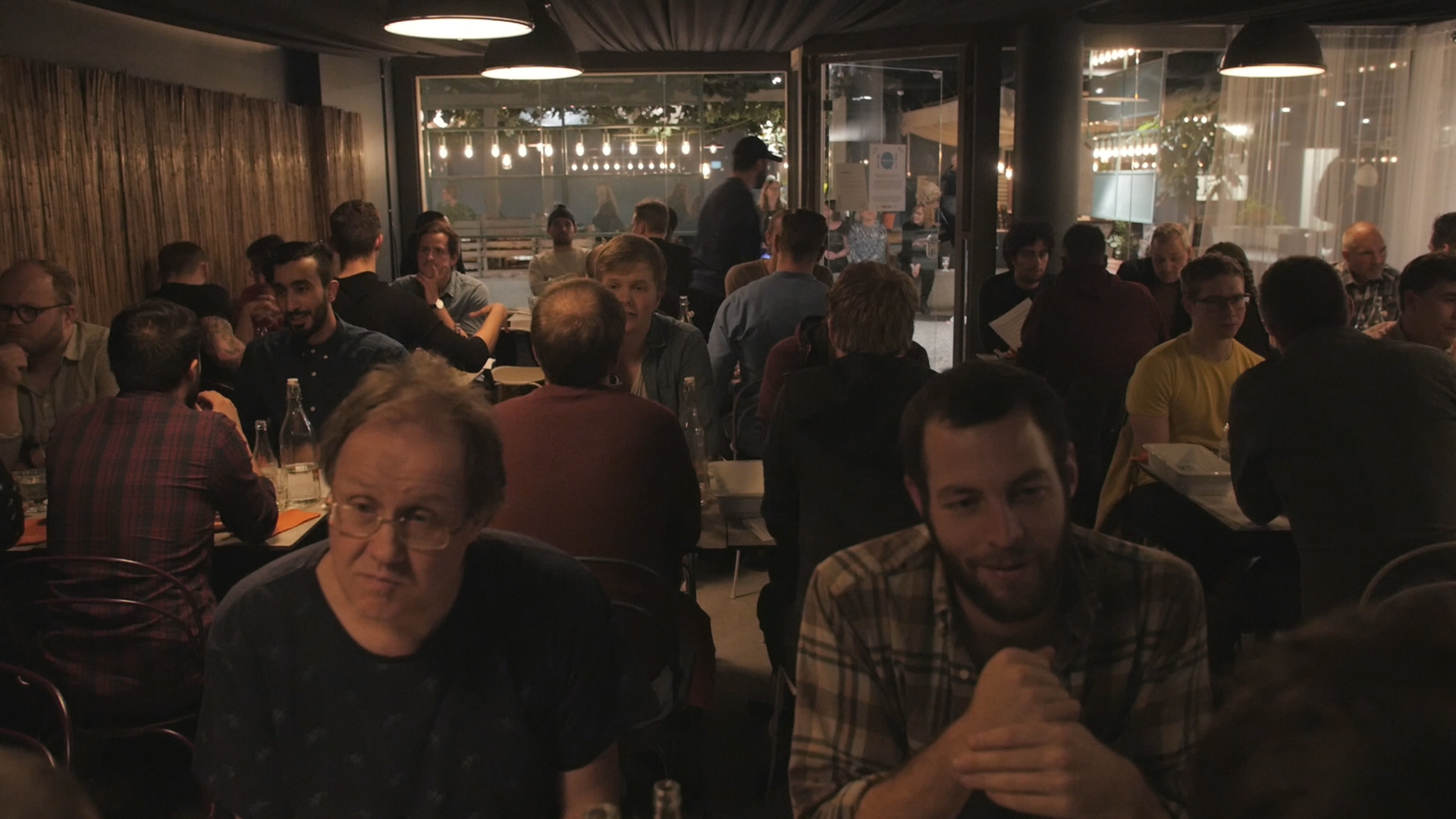bild från restaurangen där flera män sitter vid bord och pratar.